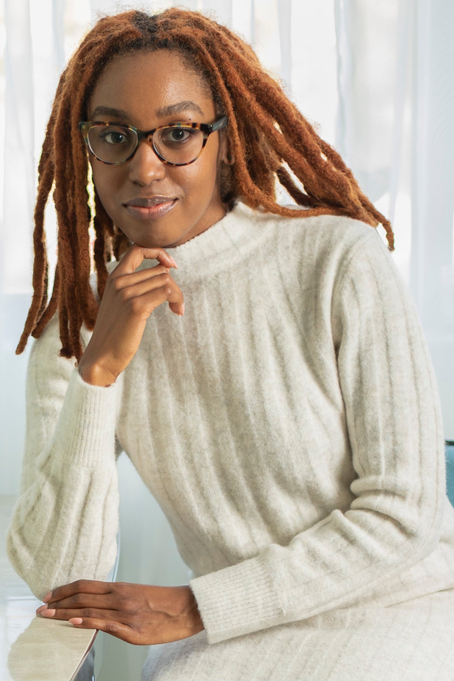 Woman wearing a white sweater sitting in a modern office setting